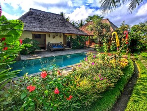 A house with a thatched roof, a swimming pool, and lush greenery. - Uma Kangin (Ubud)