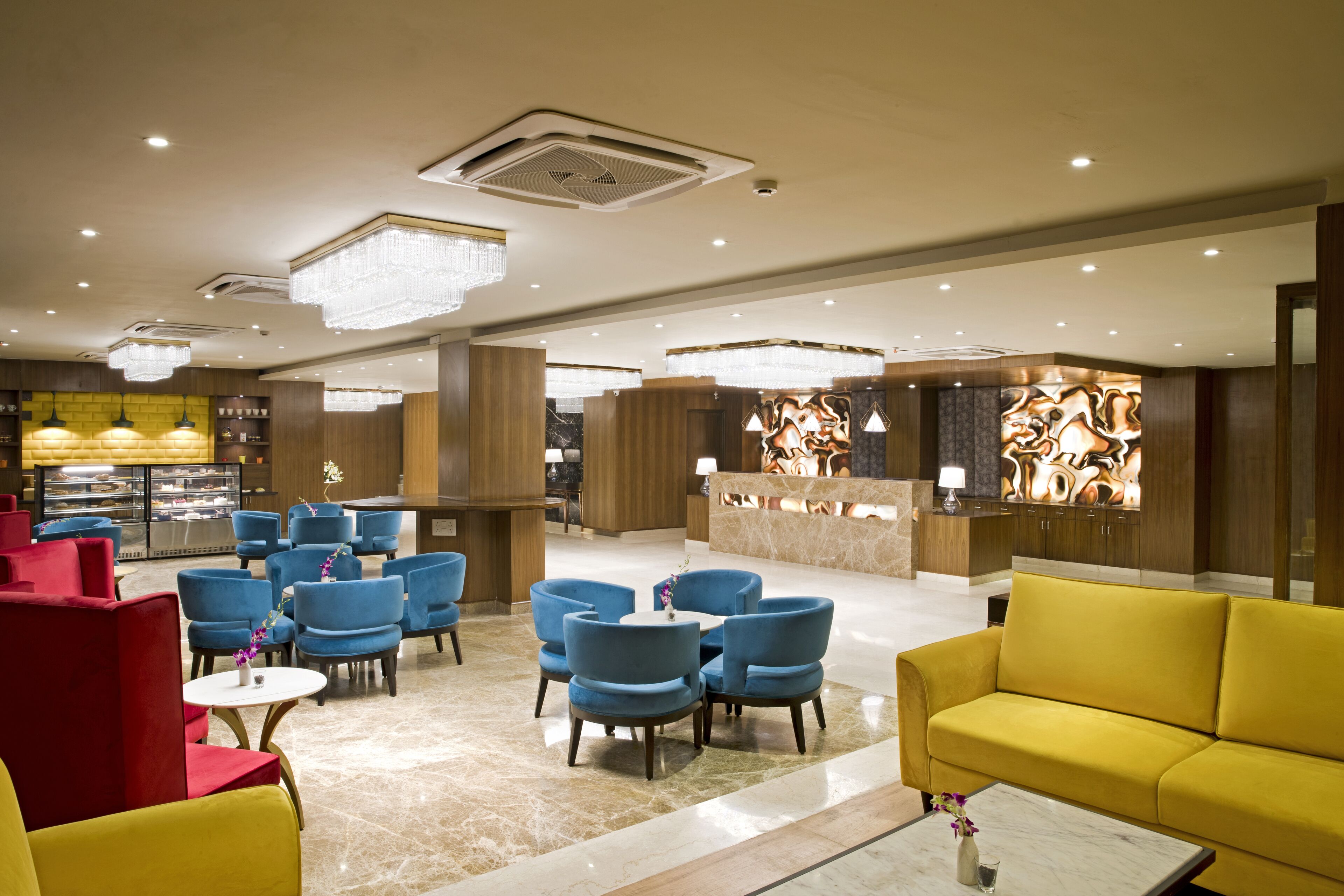 A spacious lobby with multiple seating areas, a reception desk, and a modern chandelier.