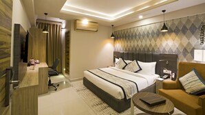 A modern hotel room with a large bed, a desk, a chair, and a sofa. - Regenta Central Noida (Noida)