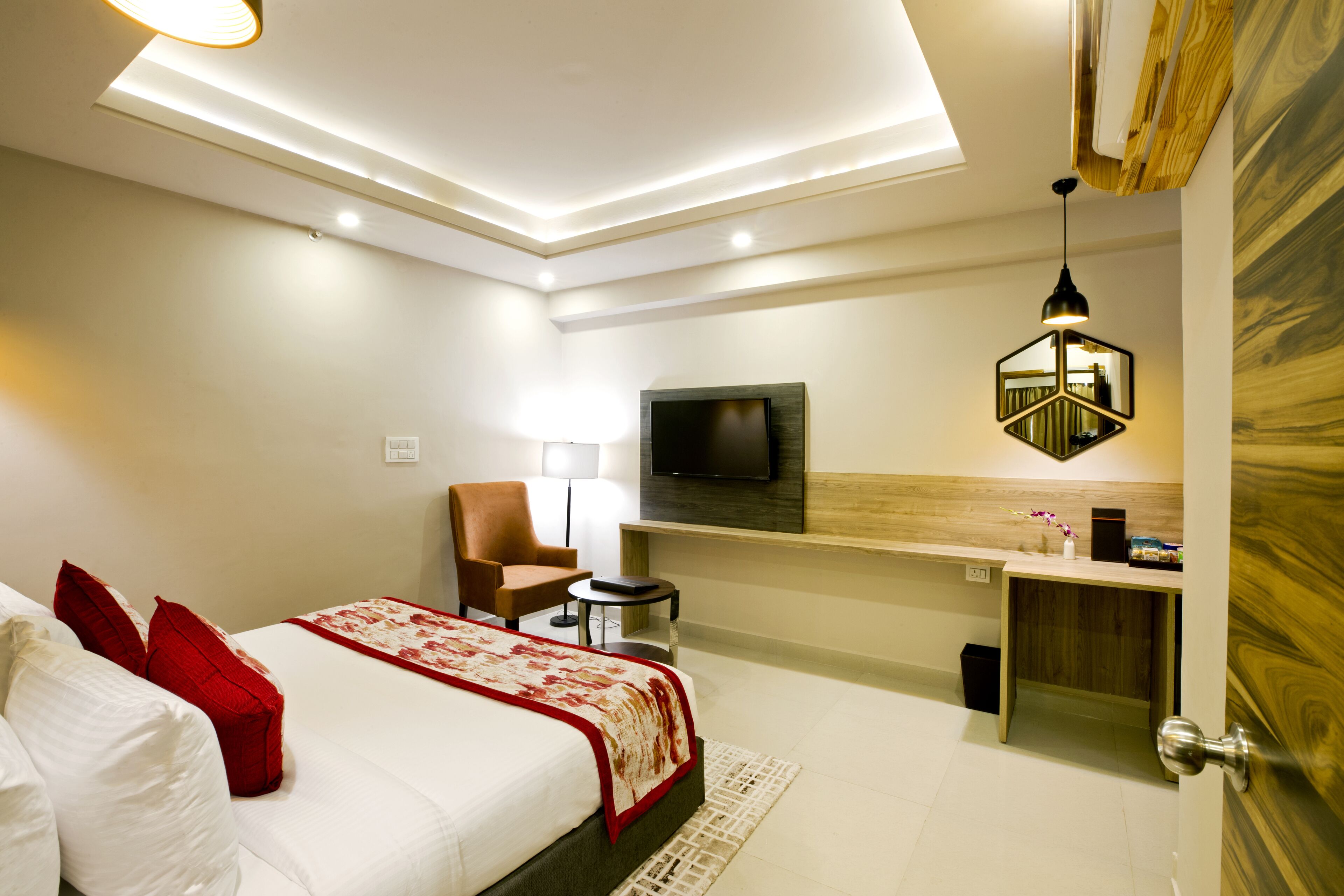 A modern hotel room with a large bed, a TV mounted on the wall, a desk, and a chair.