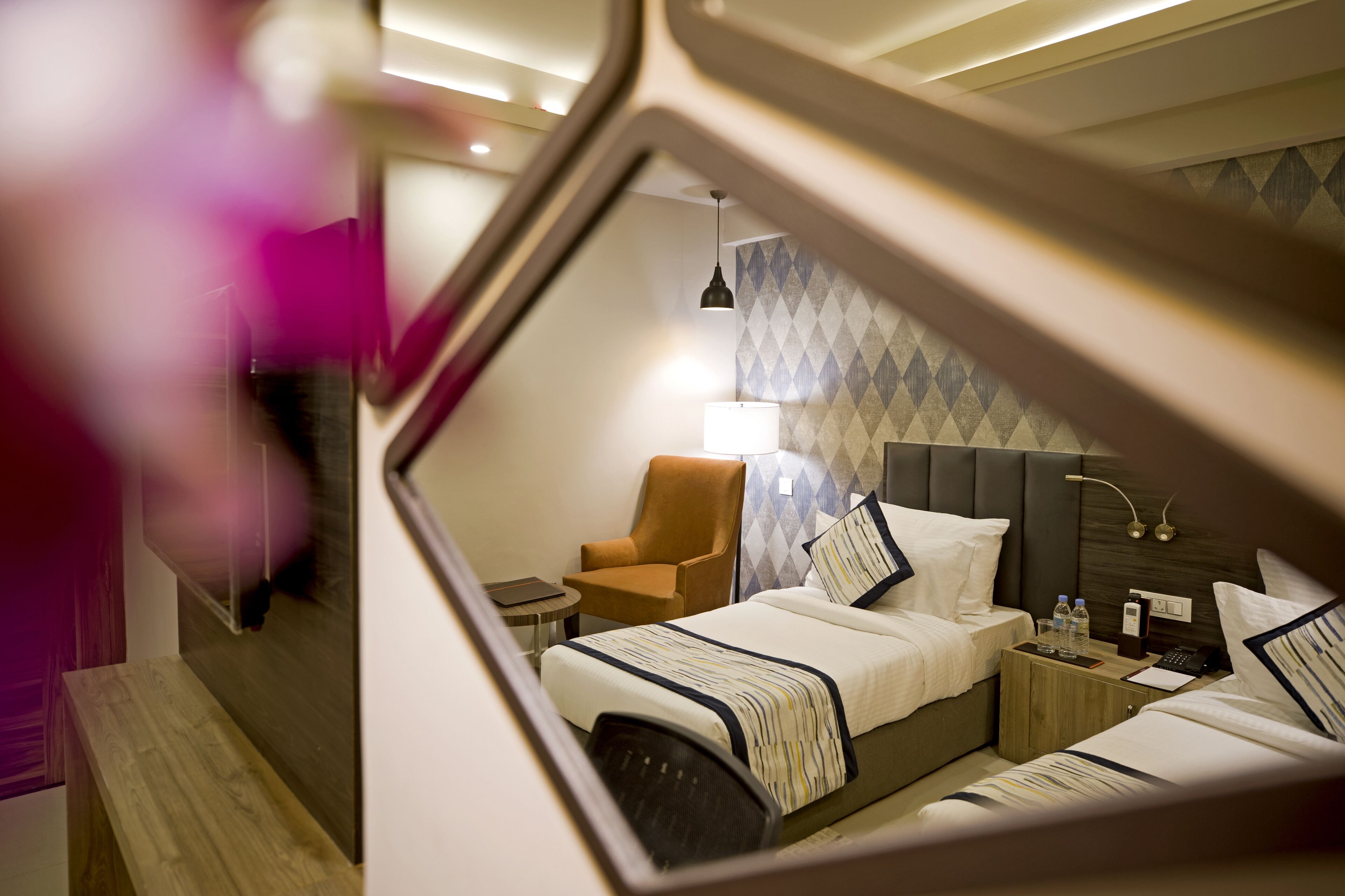 A hotel room with a bed, bedside tables, a chair, and a lamp.