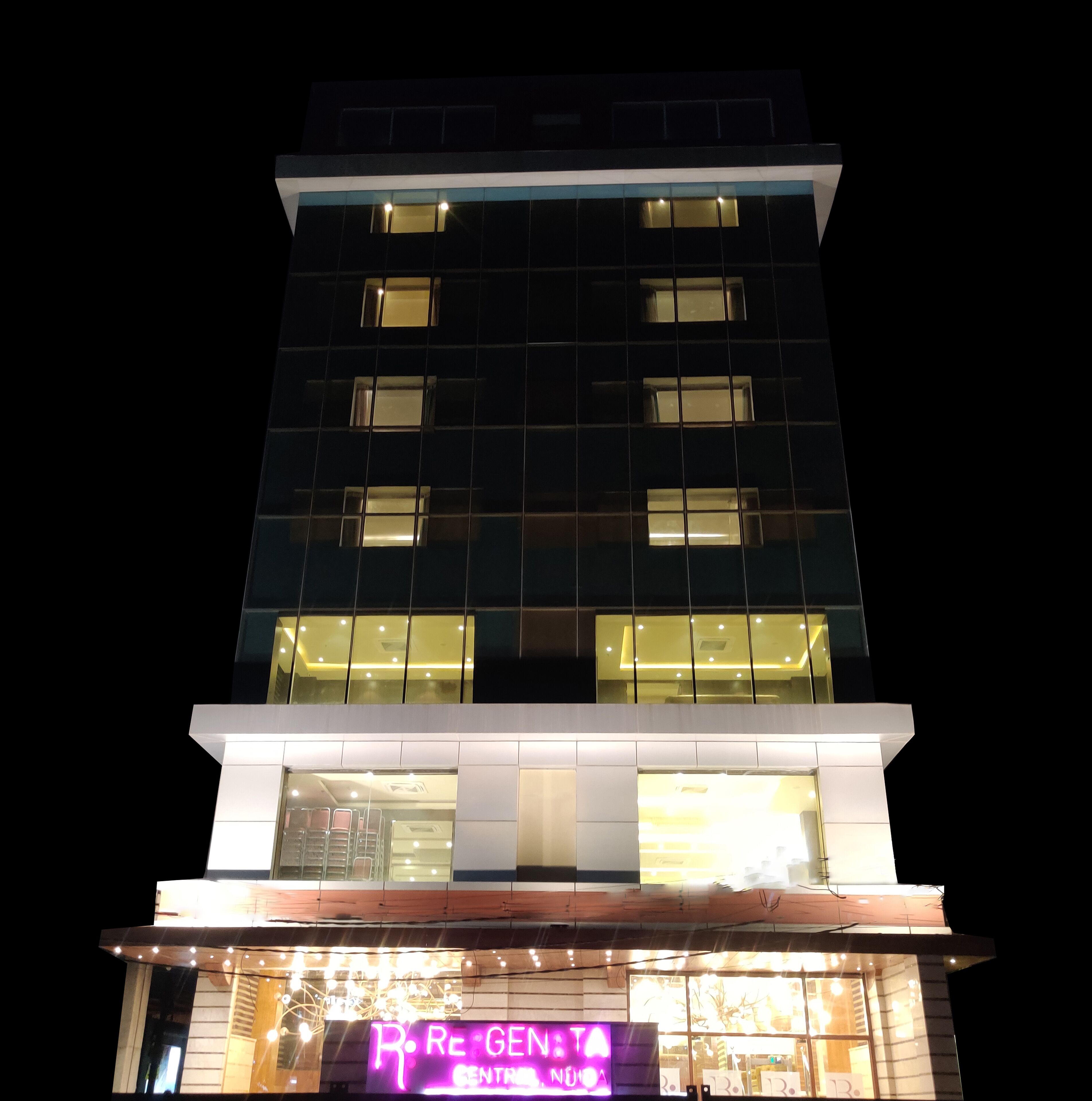 Un edificio de varios pisos con ventanas iluminadas y un llamativo letrero de neón en la planta baja.
