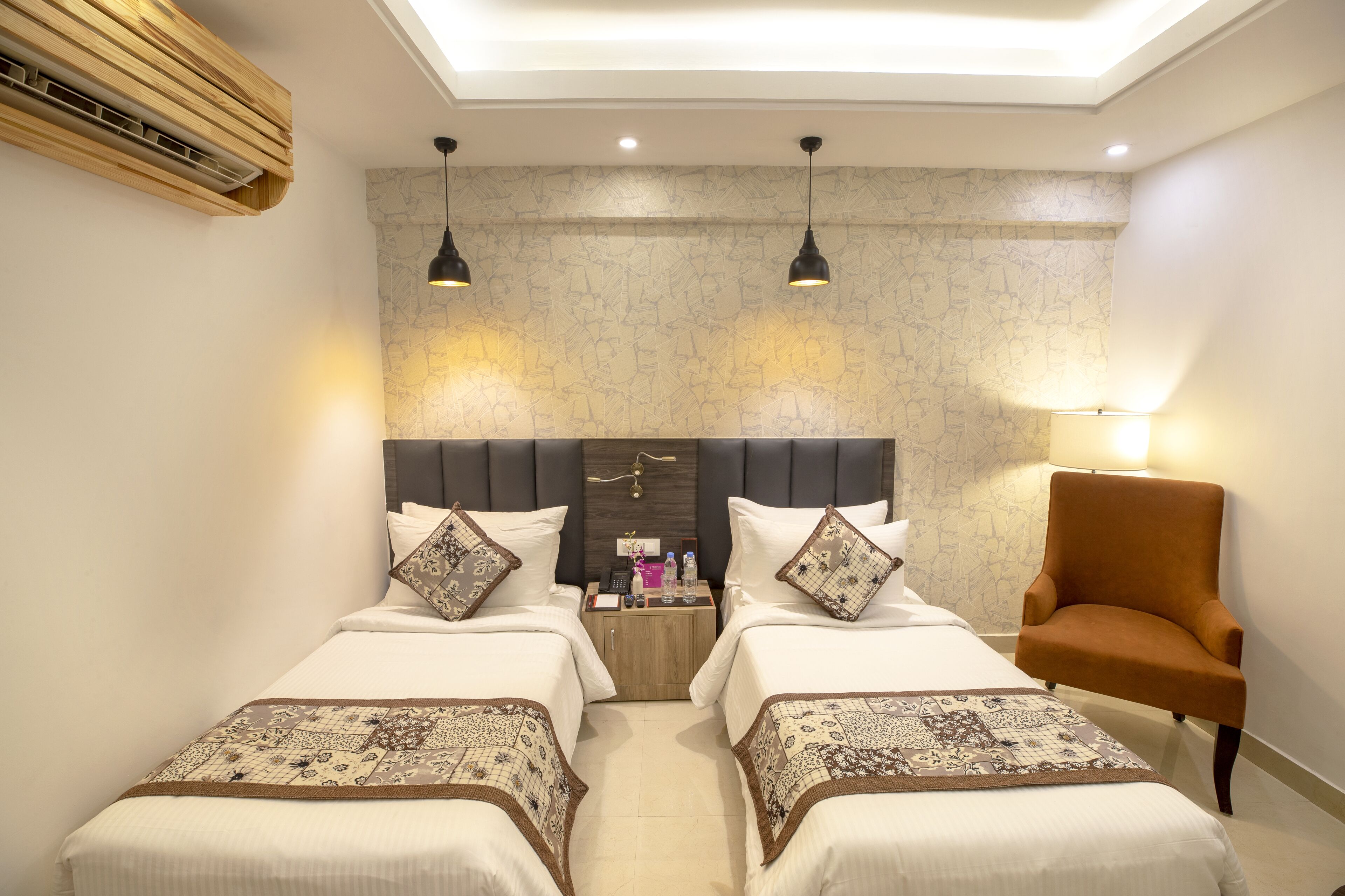 A hotel room with two beds, a wooden headboard, a nightstand, a chair, and a skylight.