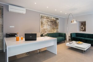 Una sala de estar moderna con un escritorio blanco, un sofá verde y un cuadro abstracto grande.