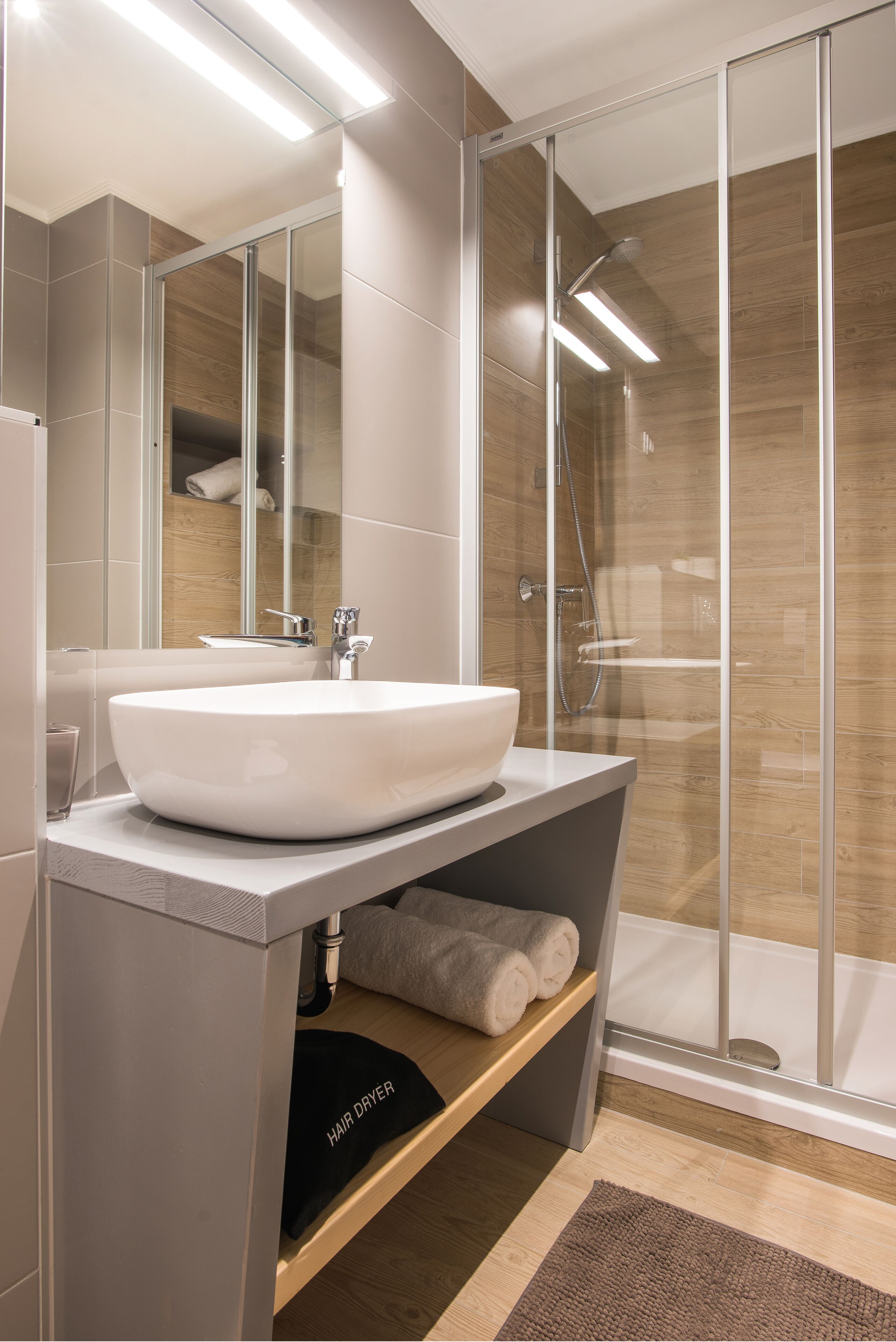 Ein modernes Badezimmer mit einem großen weißen Waschbecken, einer Duschkabine aus Glas und einem Handtuchhalter.