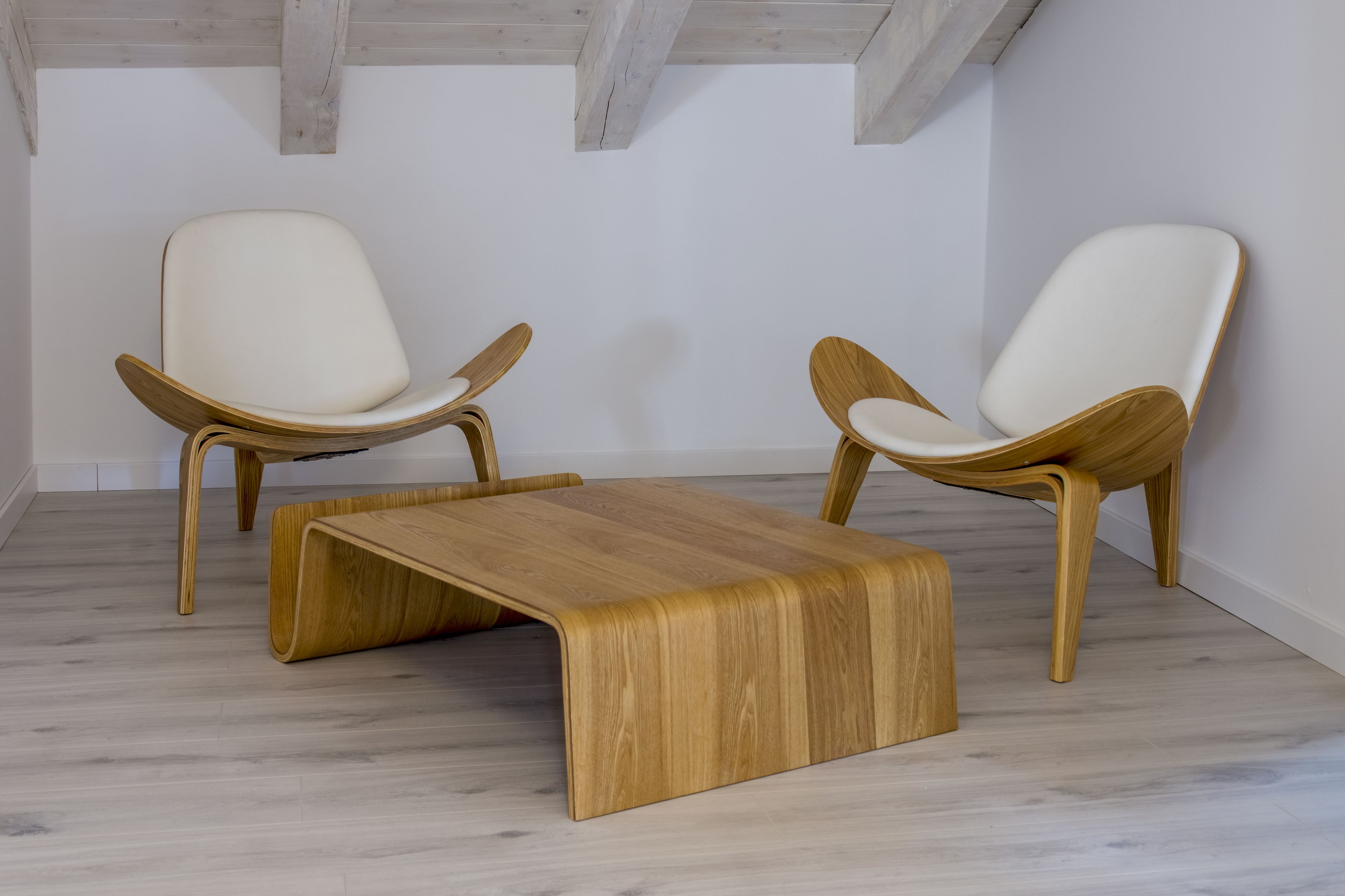 A minimalist room with two wooden chairs and a wooden coffee table.