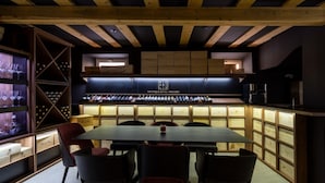 Un espace repas moderne avec une longue table et plusieurs chaises, un meuble à vin rempli de bouteilles, et une enseigne indiquant « Hôtel-boutique – Skradin ».