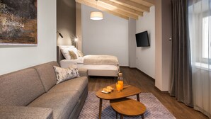 Un salon moderne avec un canapé, une table basse sur laquelle sont disposés des éléments pour le petit-déjeuner, un téléviseur et un tableau accroché au mur.