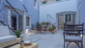 Une cour avec une table en bois, des chaises, un canapé et des plantes en pot.