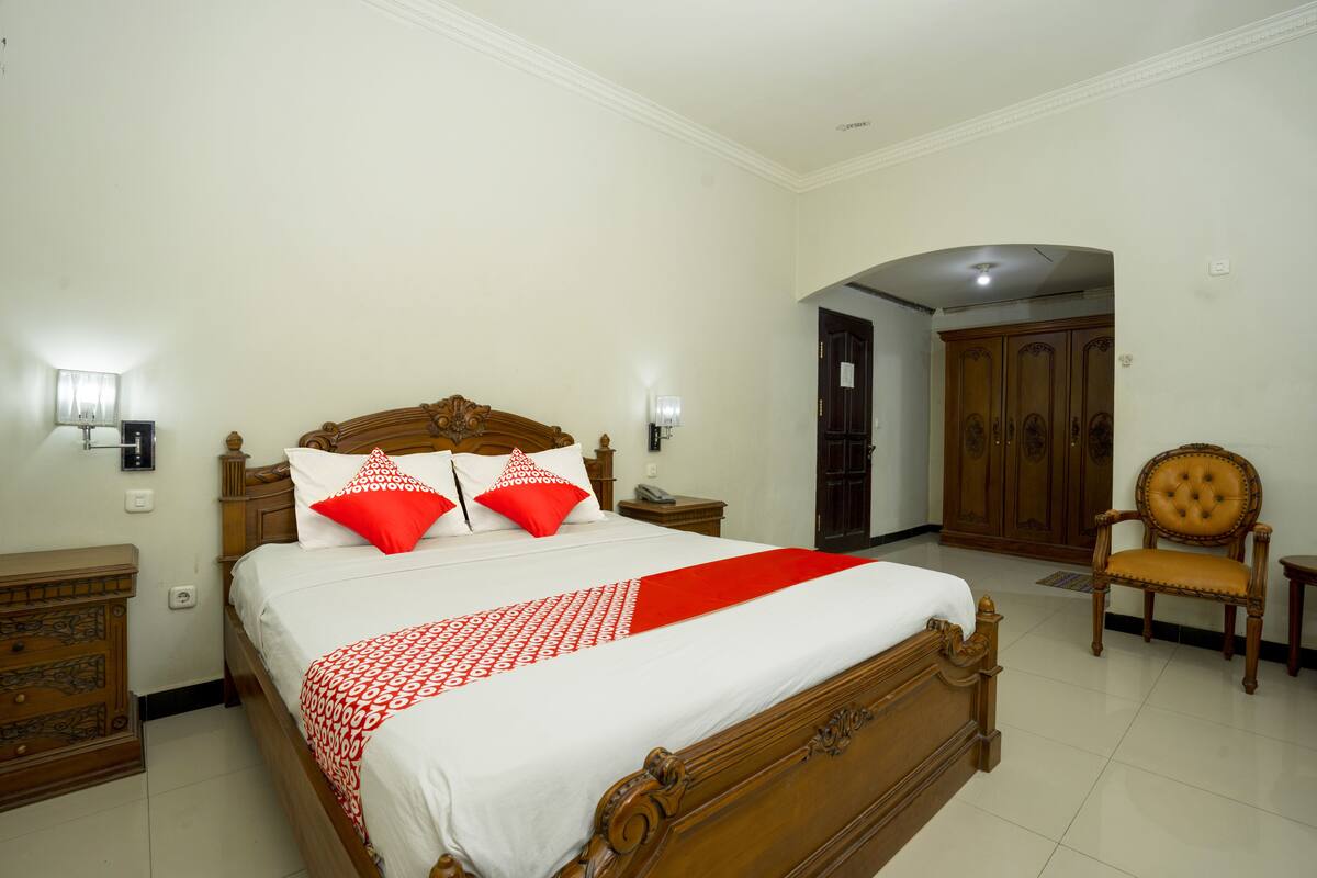 A neatly arranged bedroom with a wooden bed, two bedside tables, a chair, and a wardrobe.