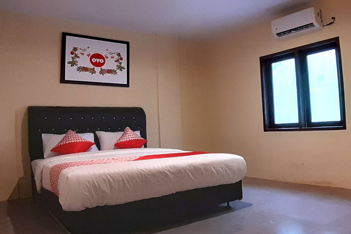 A bedroom with a bed, a framed picture on the wall, and a window.