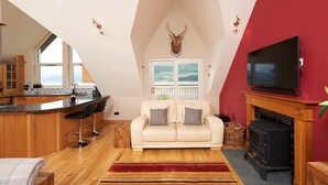 A spacious loft with a kitchen, a sofa, a fireplace, and a TV.