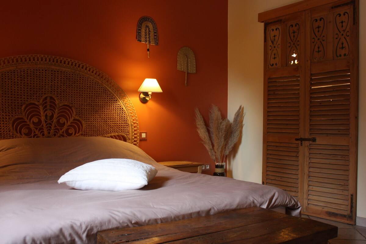 A bedroom with a wooden headboard, a bedside lamp, a wooden nightstand, and a wooden wardrobe.