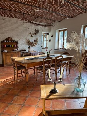 A dining area with a brick ceiling, wooden furniture, and a vase with dried plants. - L'Atterrissage (Santes)