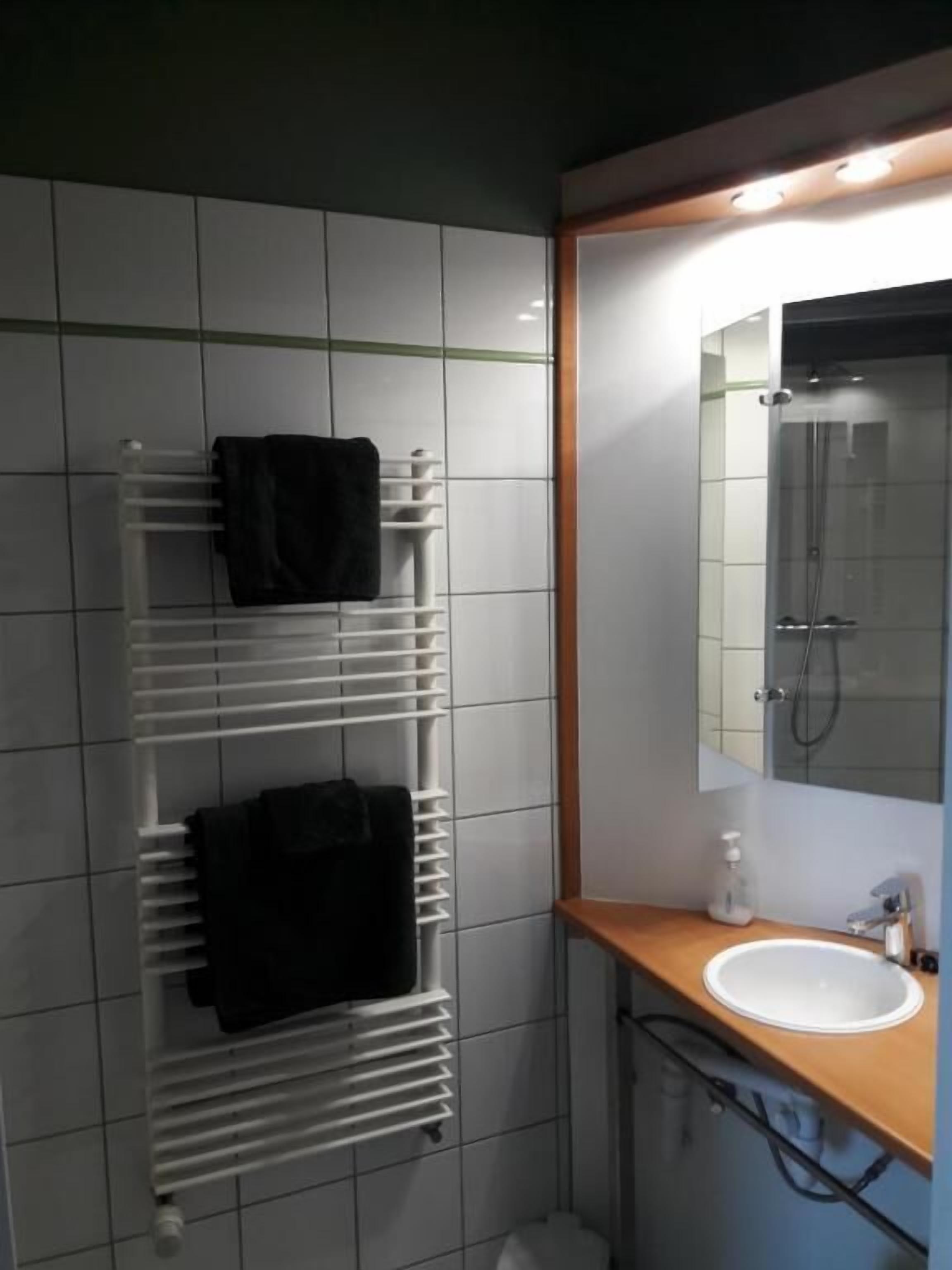 Une salle de bain avec un lavabo blanc, un miroir et un porte-serviettes avec deux serviettes.