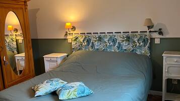 Een slaapkamer met een bed, nachtkastje, kapstok en spiegel.