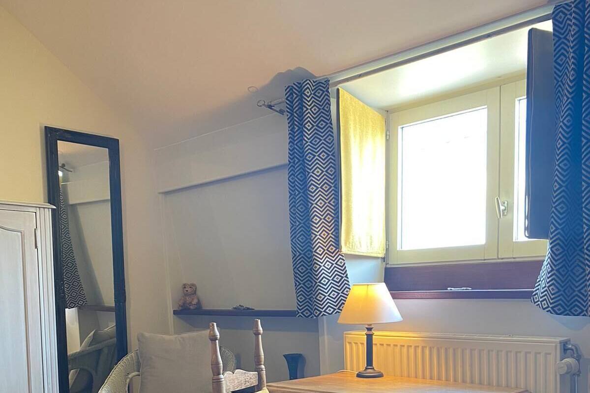 A small dining area with a table and chair, a lamp, and a window with curtains.