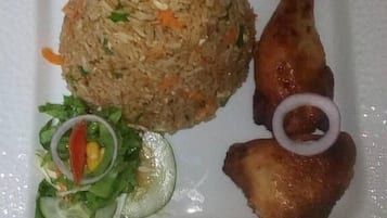 A plate with fried rice, a grilled chicken leg, and a side salad.