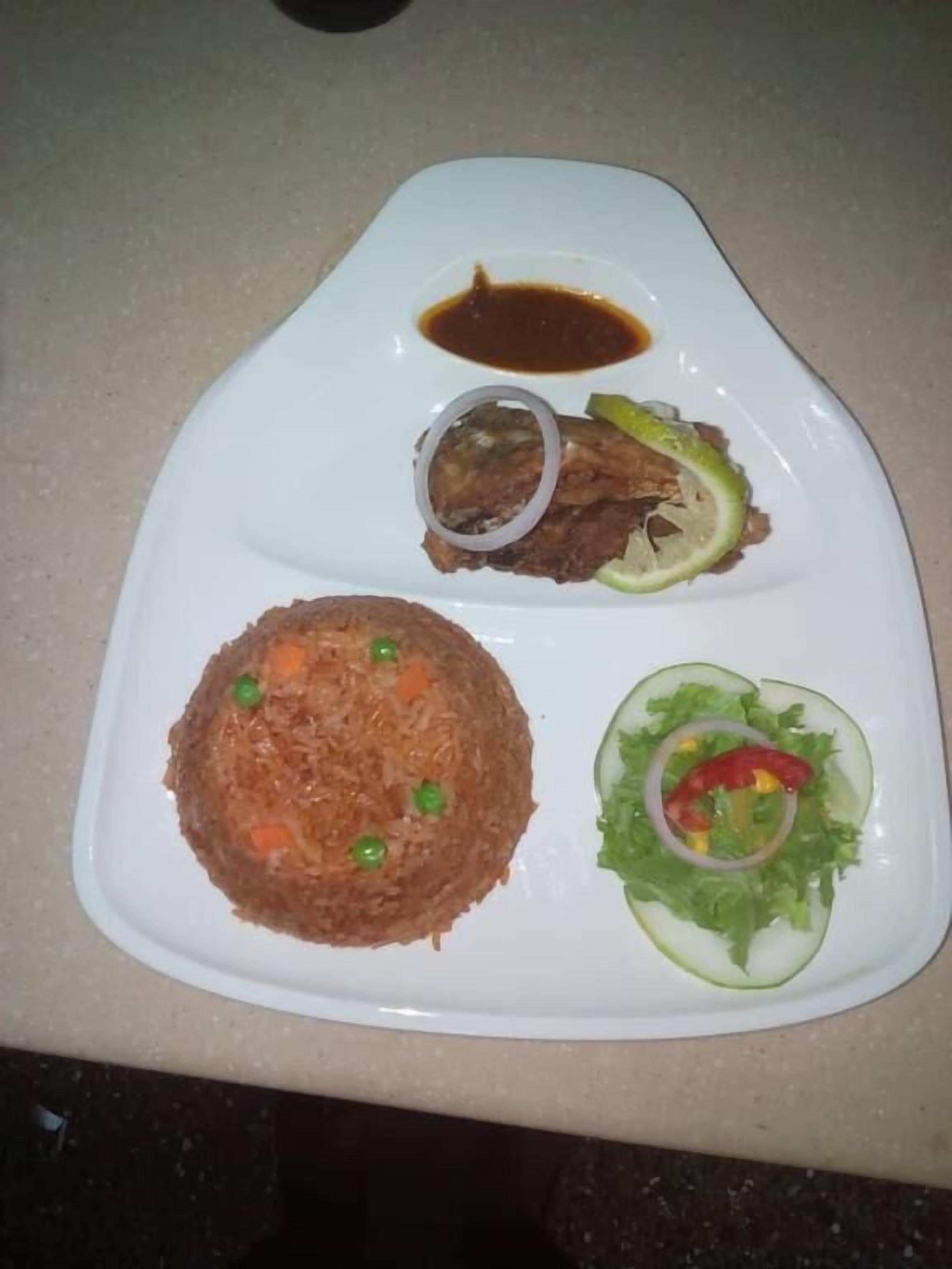 A plate with rice, meat, and salad.