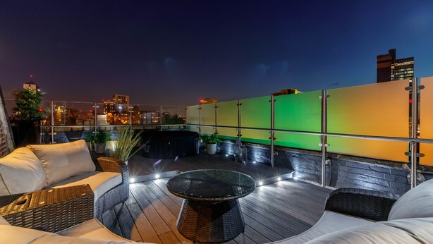 A rooftop terrace with outdoor seating, a glass table, and city views at night. - Swan Street Penthouse (Manchester)