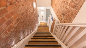 A staircase with wooden steps and white railings, flanked by brick walls. - Swan Street Penthouse (Manchester)