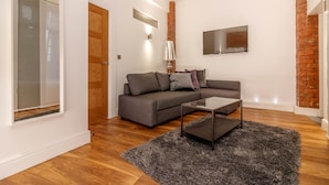 A modern living room with a grey sofa, a small coffee table, and a black rug. - Swan Street Penthouse (Manchester)