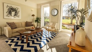 Een woonkamer met een bank, salontafel en een groot raam met uitzicht op het landschap.