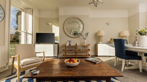 Een woonkamer met een houten salontafel, een fruitschaal, een televisie en een grote spiegel.