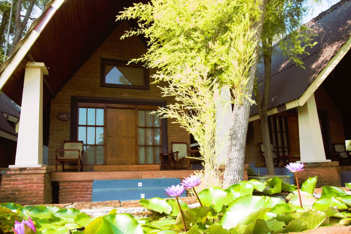 A lodge with a wooden facade, a large window, and a porch with chairs.