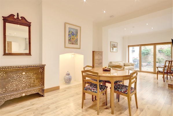 A dining area with a wooden table and chairs, a vase, and a mirror on the wall. - Luxury Apartments - Rodney Road (Cheltenham)