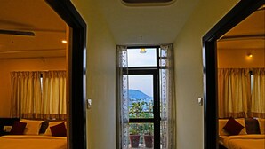 A hotel corridor with two bedrooms, each with a bed, pillows, and a view of the outdoors through a window. - Hotel Suraj Palace (Udaipur)