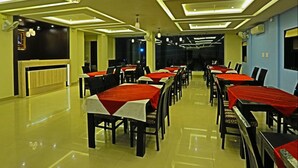 A spacious dining area with multiple tables and chairs, modern ceiling design, and a clean, reflective floor. - Hotel Suraj Palace (Udaipur)