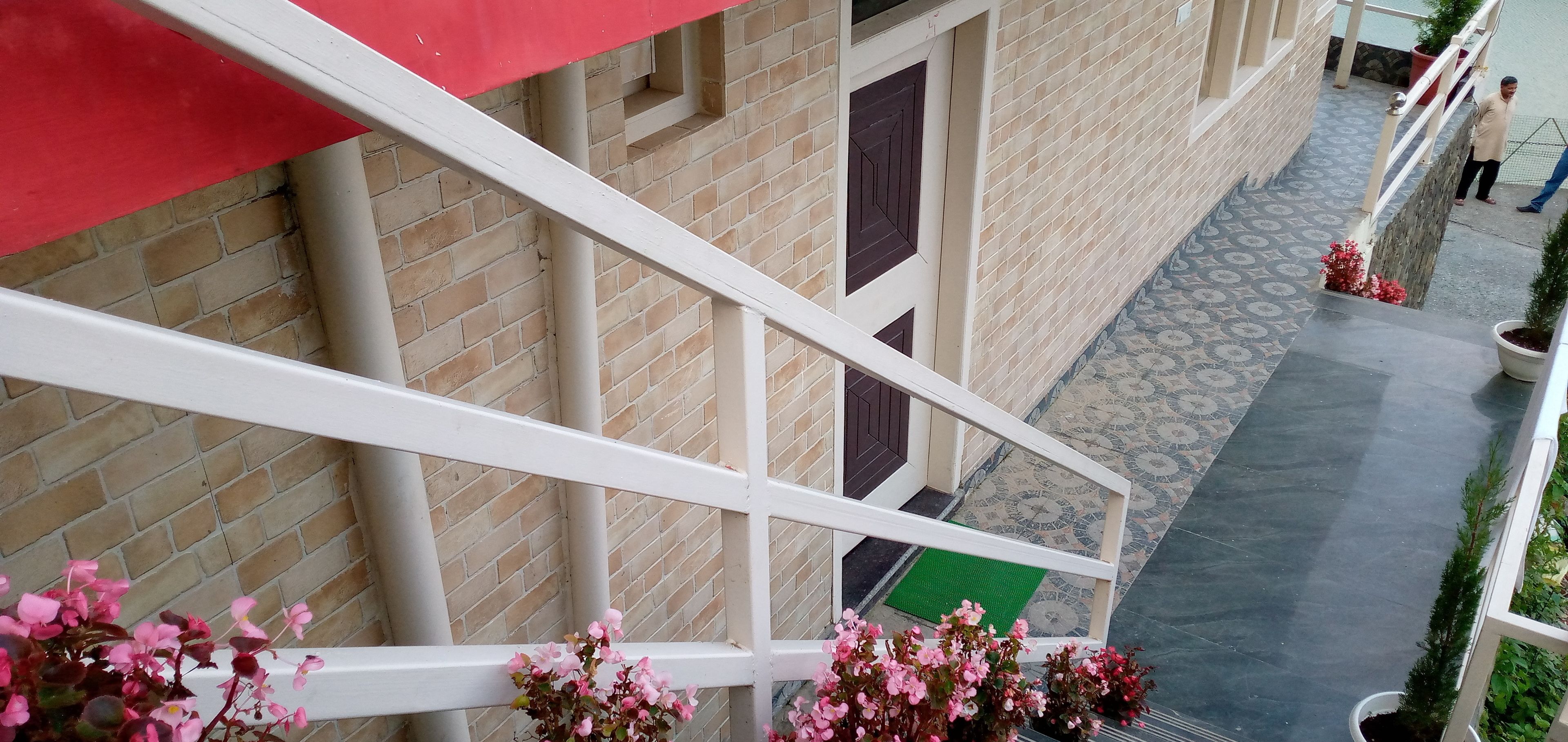A brick building with a white railing and a red awning.