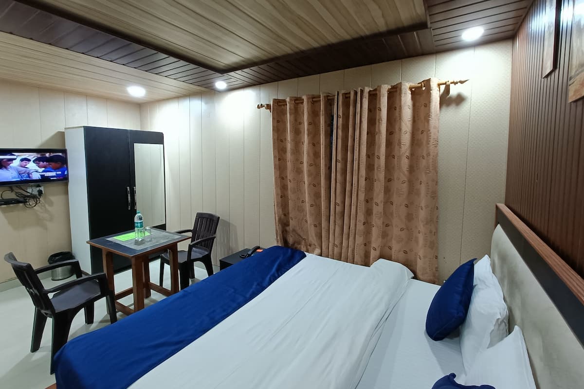 A hotel room with a bed, a desk with a chair, a television, and a wardrobe.