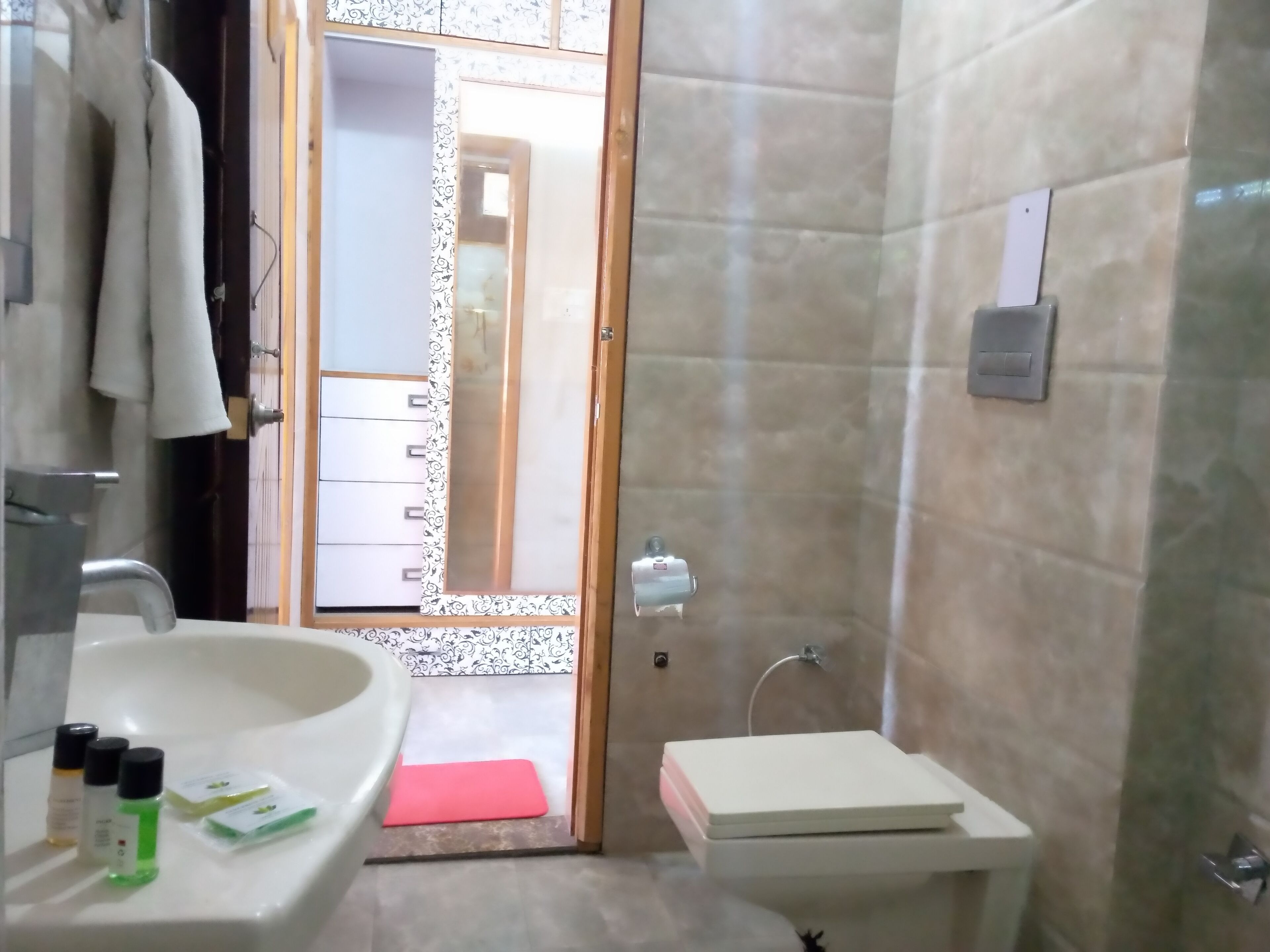 Une salle de bain équipée d’un lavabo, d’un miroir et d’un espace douche. On y trouve des articles de toilette sur le lavabo et un porte-serviettes.