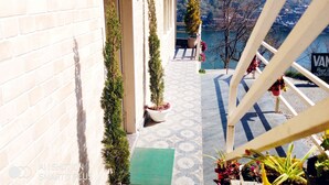 Un balcón con plantas en macetas, vista a un lago y un edificio de ladrillo.