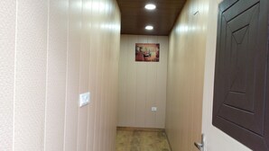 Un pasillo estrecho con paredes color beige, techo de madera y una puerta oscura a la derecha.