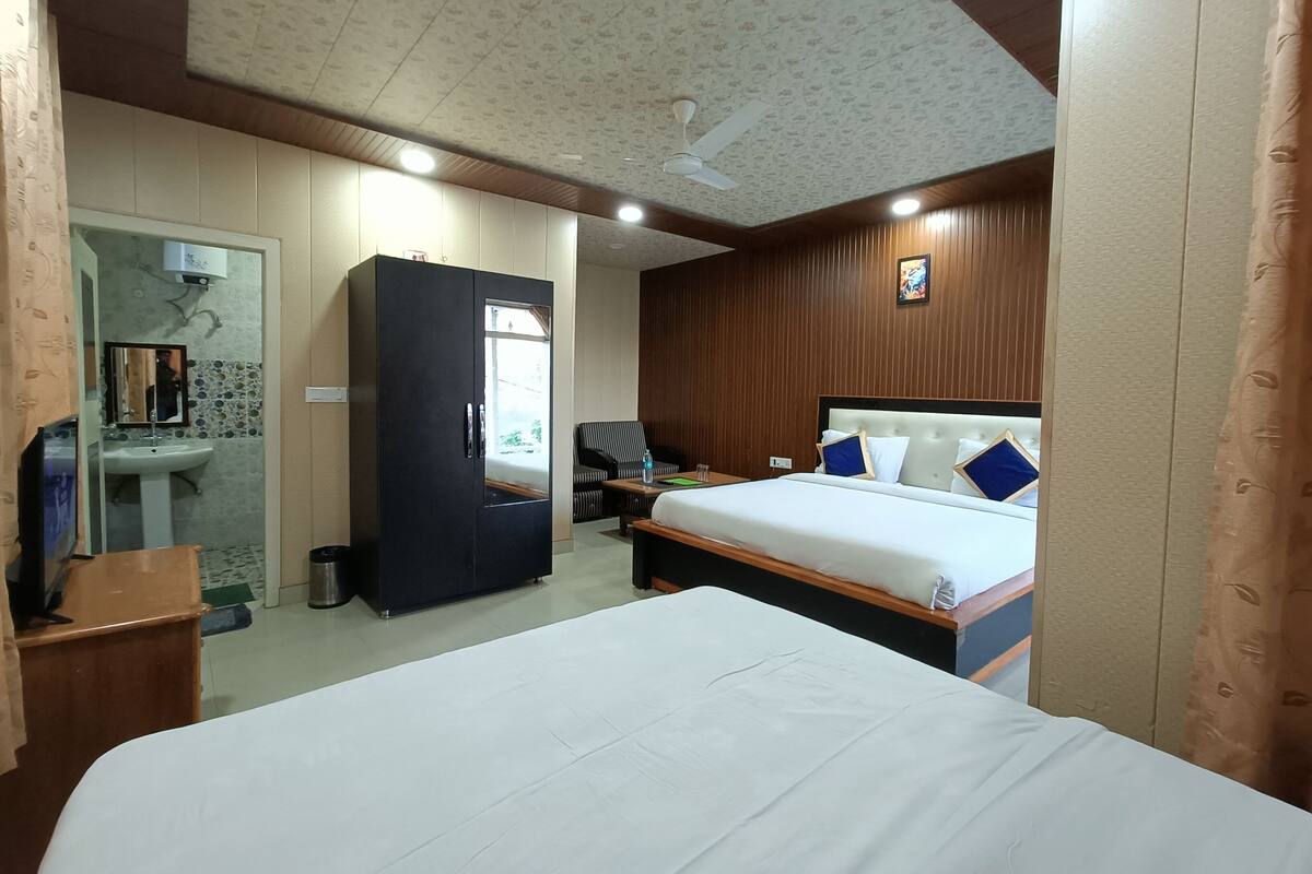 A hotel room with a bed, a wardrobe, a desk, a chair, a mirror, and a bathroom with a sink and a toilet.