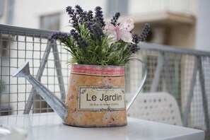A potted plant with lavender and a butterfly on a metal table with a watering can. - Acropolis Heart (Athens)
