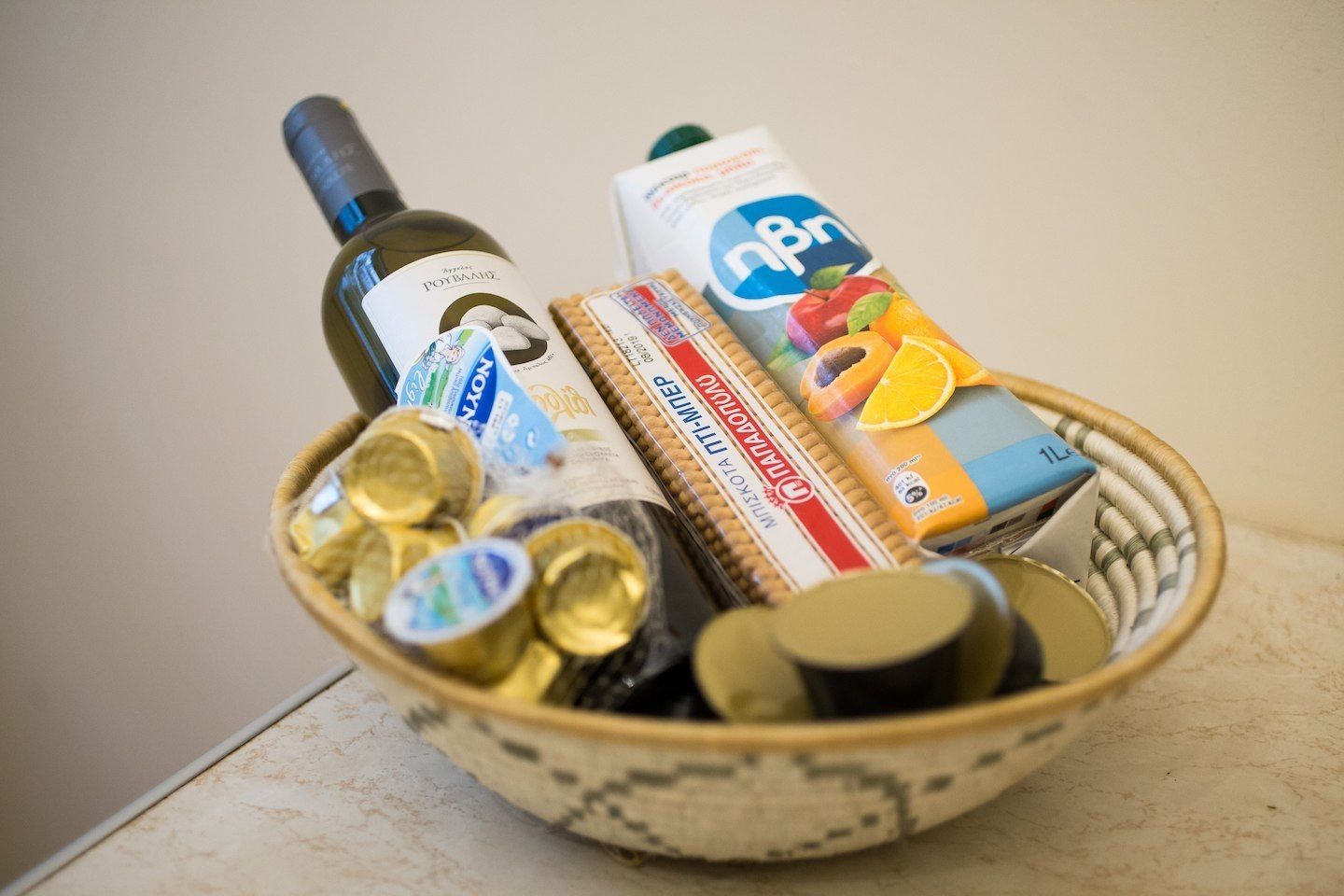 Una cesta con una botella de aceite de oliva, un cartón de leche, una caja de cereales y varias latas de cerveza vacías.