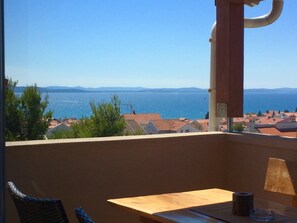 Un balcón con vista al mar y montañas a lo lejos.