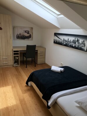 A bedroom with a skylight, a desk with a chair, a bed, and two paintings on the wall. - Apartments Four You (Zadar)