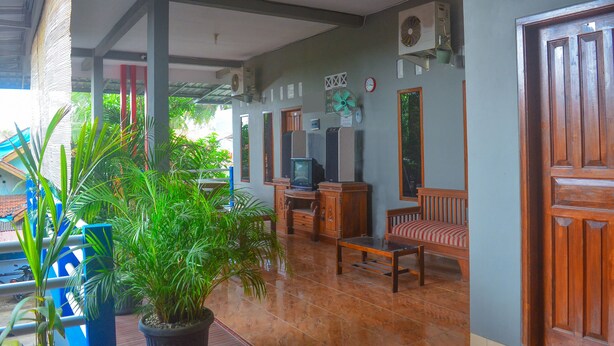 A spacious living area with a wooden cabinet, a television, and a comfortable seating area. - OYO 1145 Rita Guesthouse (Pangandaran)