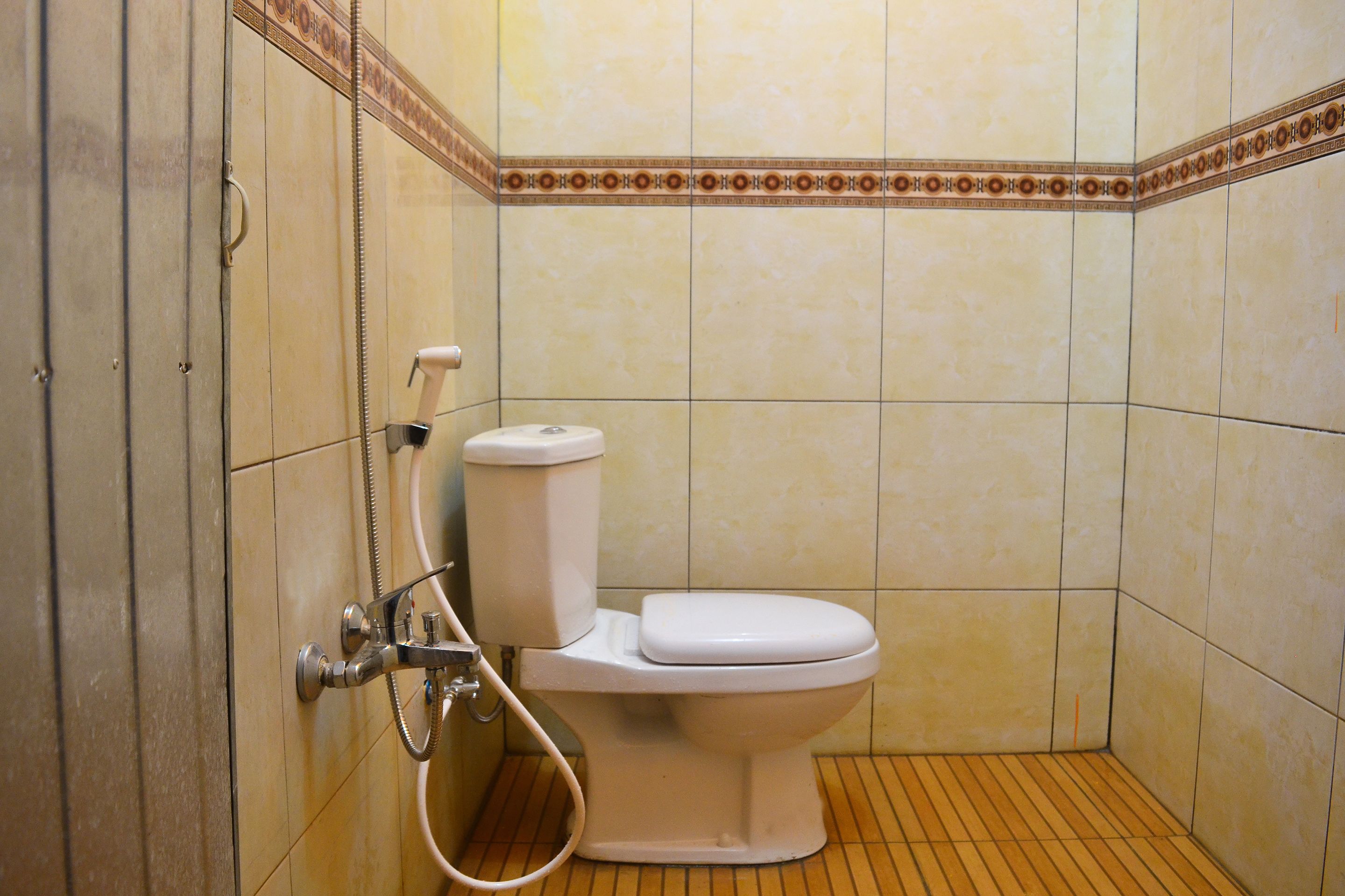 A small, tiled bathroom with a toilet and a shower.