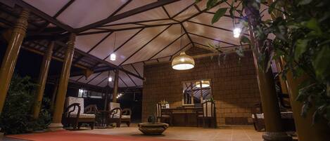 A covered outdoor area with a brick wall, wooden furniture, and a hanging light fixture.