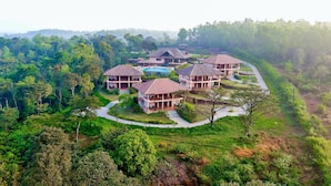 A resort with multiple villas, a swimming pool, and lush greenery surrounding the property.