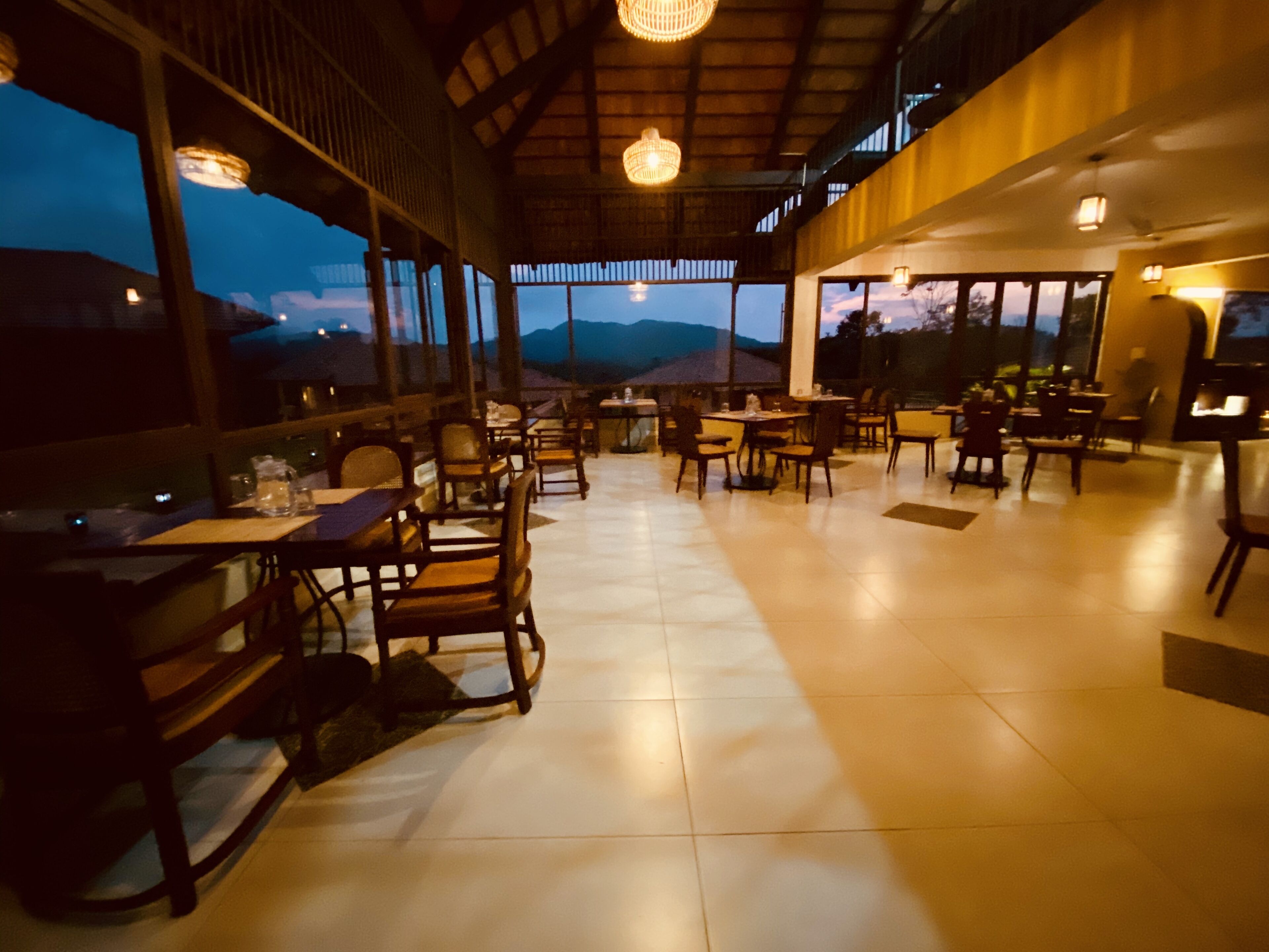 A restaurant with a view of mountains, wooden furniture, and large windows.