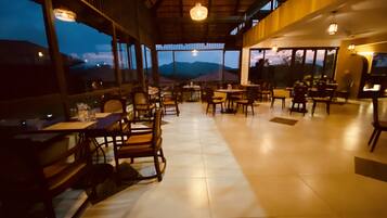 A restaurant with a view of mountains, wooden furniture, and large windows.