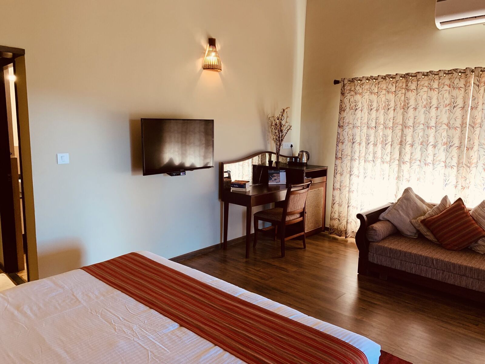 A hotel room with a bed, a desk with a chair, a television, and a sofa.