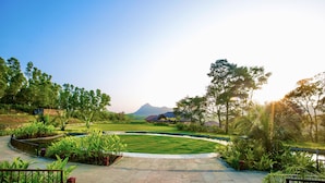 A paved pathway leading to a grassy area with a mountain in the background.
